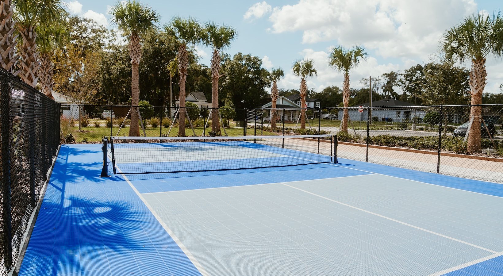 The outdoor recreation area at The Allen Apartments in Kissimmee, FL, featuring pickleball courts and palm trees.